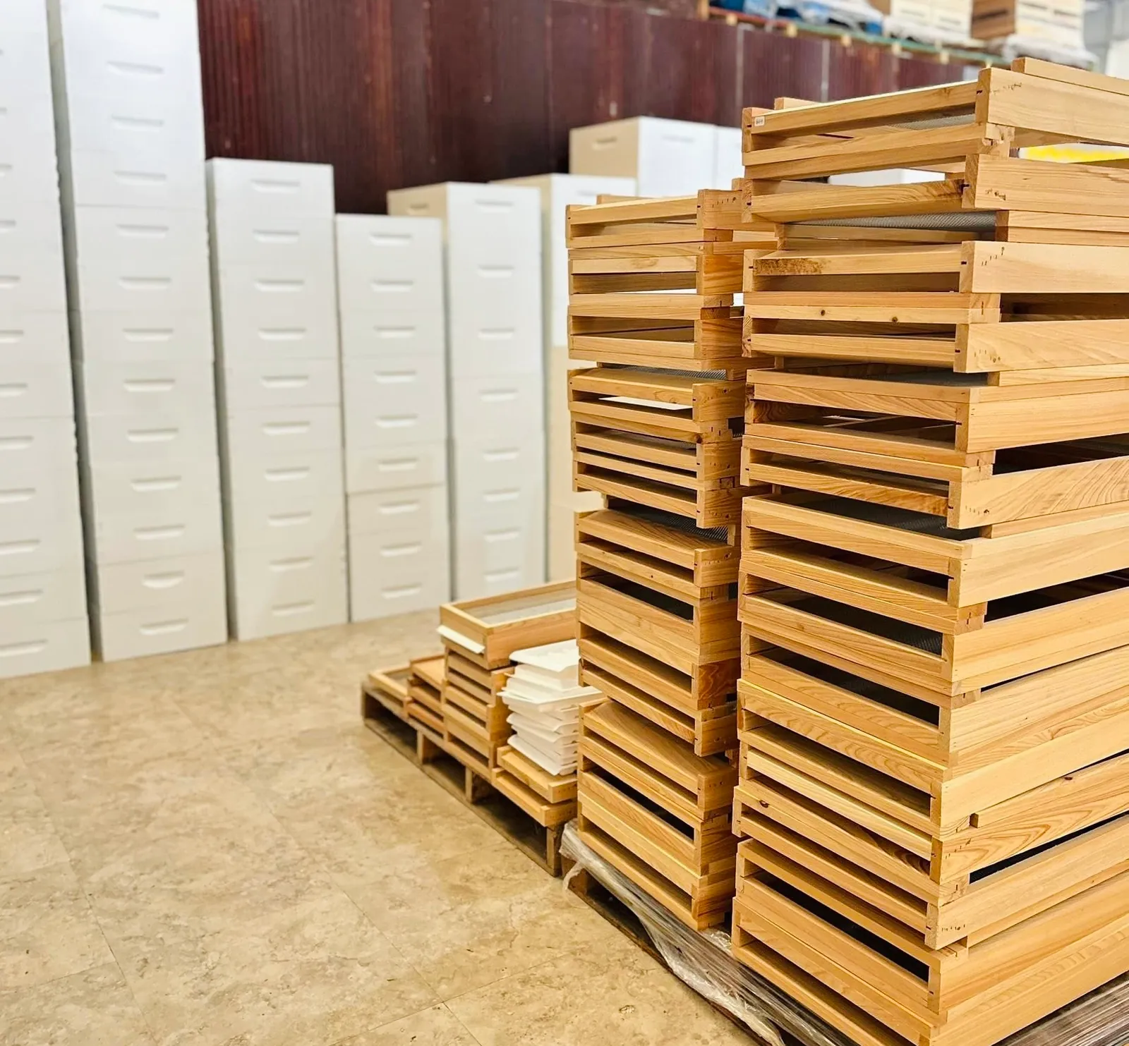 Stacks of wooden hive bodies and frames beside painted white hive boxes at Overflow Honey Co.
