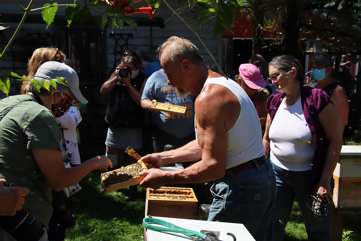 A beekeeping class inspecting a frame outdoors