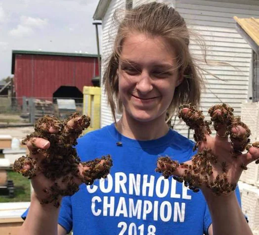 A visitor with bees covering her gloved hands
